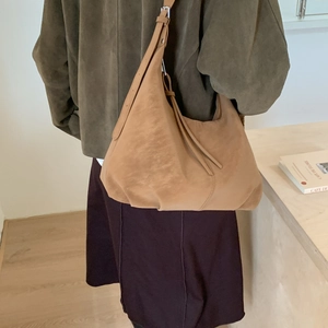 Detailed view of brown suede hobo bag with adjustable strap worn by a model in interior
