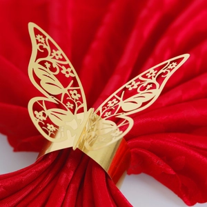 Macro detail of laser-cut golden butterfly napkin ring on elegant red silk fabric