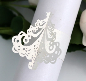 Macro detail of laser-cut pearl paper napkin ring with Christmas tree hollow design