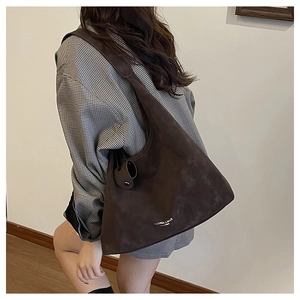 Gros plan d'un grand sac hobo en daim marron foncé montrant sa texture et son logo mode