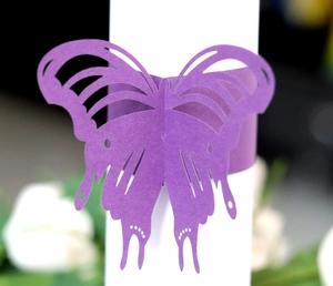 Macro detail of purple laser-cut paper butterfly napkin ring with hollow patterns