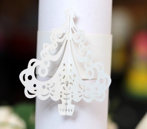 Macro detail of white laser-cut Christmas tree napkin ring with intricate hollowed patterns