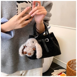 Detail of black leopard print bucket bag featuring a plush rabbit pendant and silver buckle
