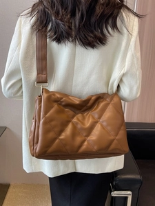 Brown quilted crossbody tote bag with oversized rhombus stitching and wide shoulder strap