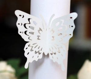 Macro detail of laser-cut butterfly napkin ring in ivory white with intricate patterns