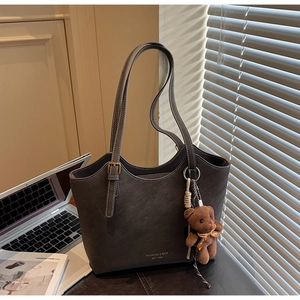 Détail d'un grand sac cabas marron café avec lettrage doré et un petit pendentif ours en peluche