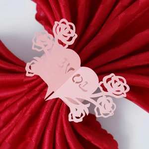 Detail of pink laser-cut paper napkin ring with rose patterns and LOVE lettering