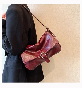 Detail shot of vintage burgundy shoulder bag with metallic buckle and wrinkled texture