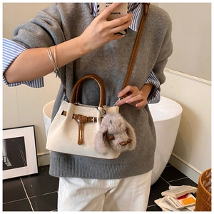 Detail of beige suede crossbody bag with brown leather handles and rabbit charm