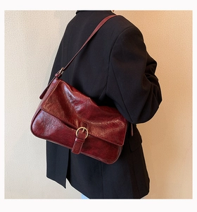 Close-up of deep red vintage faux leather shoulder bag with gold ring buckle detail
