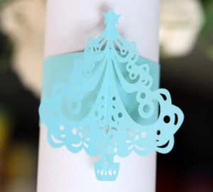 Macro detail of laser cut light blue Christmas tree paper napkin ring with star cutout
