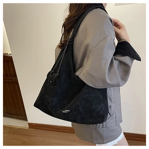 Détail du grand sac cabas en daim noir avec texte de mode porté à l'épaule