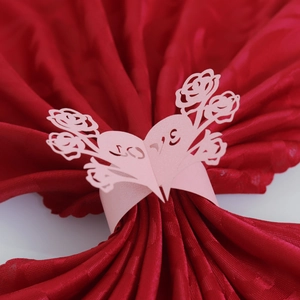 Macro detail of laser-cut pink paper napkin ring with LOVE hearts and rose patterns