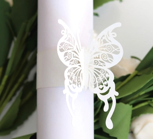 Detailed close-up of a white laser-cut butterfly napkin ring with intricate patterns