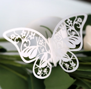 Macro detail of laser-cut ivory butterfly napkin ring with intricate floral patterns