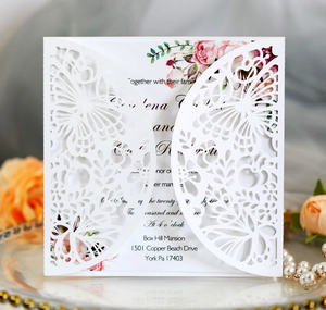 Close-up of laser-cut butterfly wedding invitation with floral inner card on mirror tray