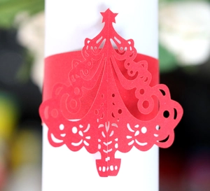 Macro detail of a laser-cut red Christmas tree paper napkin ring with floral cutouts