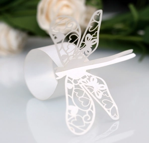 Detailed laser-cut white paper dragonfly napkin ring with delicate hollowed heart patterns