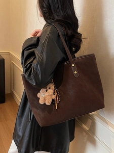 Große dunkelbraune Shopper-Tasche aus Mattleder mit Bärenanhänger am Model