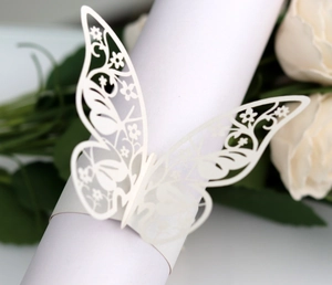 Macro shot of laser-cut white paper butterfly napkin ring with floral hollow patterns
