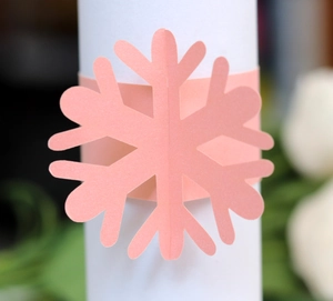 Pink paper snowflake napkin rings with laser-cut design for Christmas party table decor