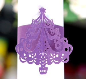 Macro detail of laser-cut purple paper napkin ring featuring a Christmas tree design