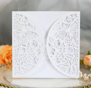 Close-up of white laser-cut wedding invitation featuring intricate butterfly and floral patterns