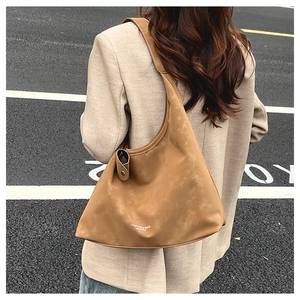 Sac hobo en daim marron avec texte porté par un mannequin dans un look de style urbain