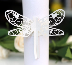 Macro shot of white laser-cut dragonfly napkin ring with delicate floral wing patterns
