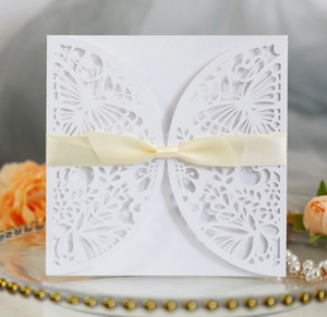 Intricate laser-cut butterfly invitation card with a cream satin bow and floral pattern