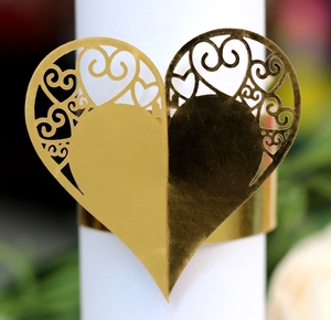 Close-up of golden hollow heart napkin ring with intricate laser-cut floral patterns