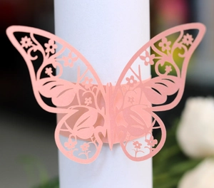 Detailed close-up of a pink laser-cut butterfly napkin ring with intricate floral patterns