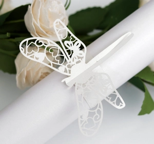 Detail of white laser-cut dragonfly napkin ring with intricate hollow floral patterns