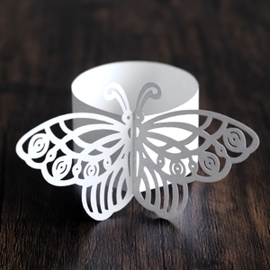 Macro shot of laser-cut white paper butterfly napkin ring with hollow geometric wing patterns