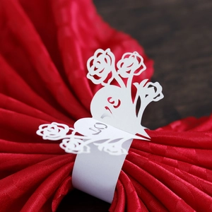 White laser-cut paper napkin ring featuring floral pattern and number 50 on red napkin
