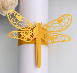 Macro view of golden dragonfly laser-cut paper napkin ring for elegant wedding party decor