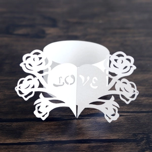 Detailed laser cut white paper napkin ring with rose and LOVE heart patterns