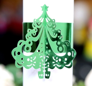 Detail of laser-cut green Christmas tree napkin ring with metallic hollow-out design