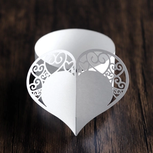 Macro view of white laser-cut paper napkin ring with intricate hollow heart-shaped pattern