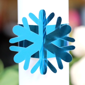 Macro detail of a bright blue 3D snowflake napkin ring on a white napkin roll