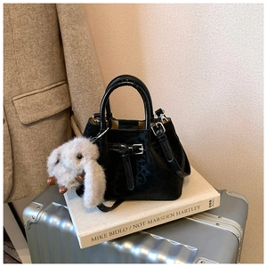 Detail of black pleated handbag with plush rabbit charm on vintage books background