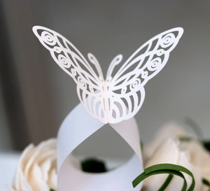 Macro detail of laser-cut white paper butterfly napkin ring with intricate hollow floral patterns