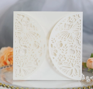 Detail of white laser-cut invitation card with butterfly patterns on a decorative tray