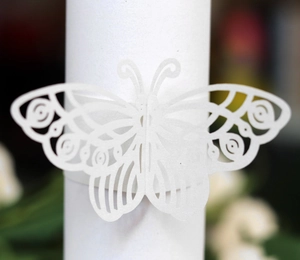 Close-up of laser-cut white paper butterfly napkin ring with intricate hollow texture