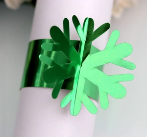 Macro shot of green metallic laser-cut snowflake napkin ring on white fabric