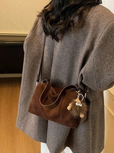 Dark brown suede boston bag with plush monster charm and adjustable shoulder strap