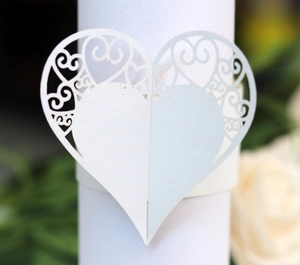 Detail of laser-cut heart napkin ring with elegant floral hollow patterns for weddings