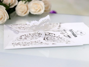 Macro view of laser-cut butterfly detail on high-end white wedding invitation card