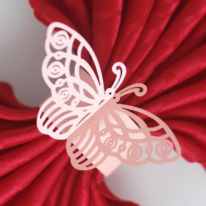 Close-up of pink laser-cut butterfly napkin ring with hollow patterns on red napkin