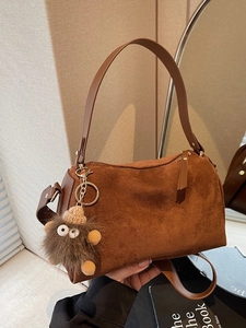 Brown suede pillow handbag with fuzzy monster charm and leather shoulder strap